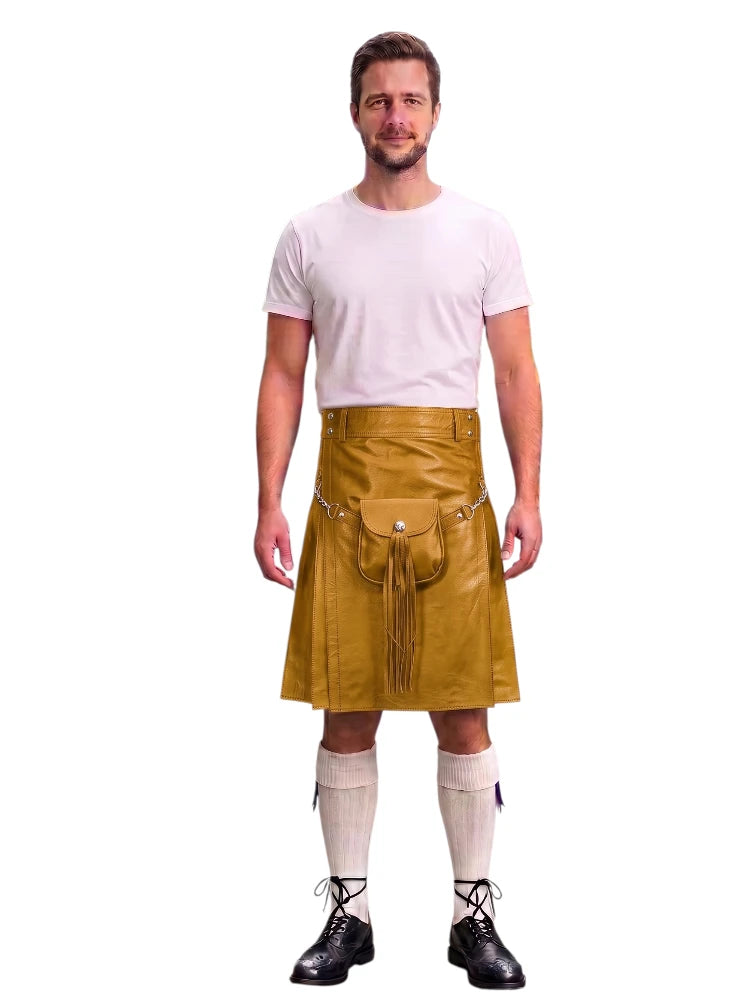 A man modeling a mustard yellow faux-leather kilt with a front pouch and tassel detail, paired with a white t-shirt, white knee-high socks, and black lace-up boots, against a plain white background.