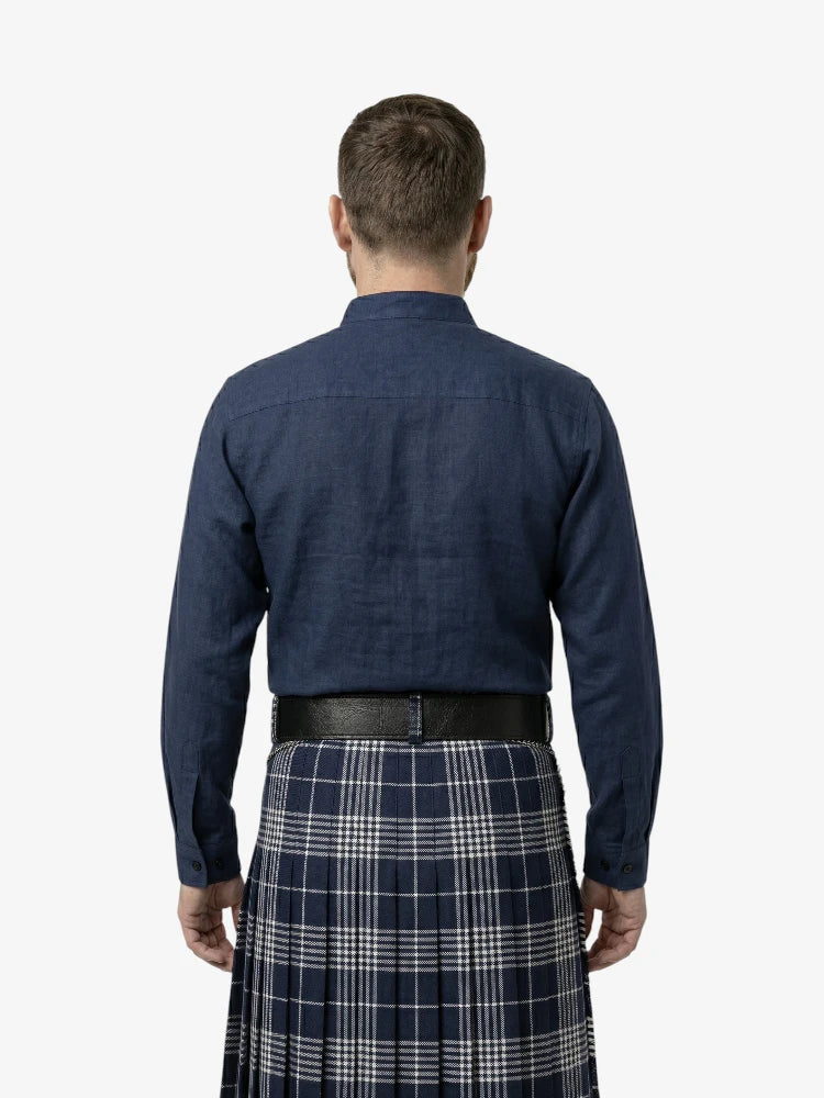 Man wearing a navy shirt and plaid kilt on a white background