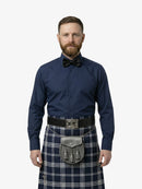 Man wearing a navy shirt, bow tie, and tartan kilt on a white background