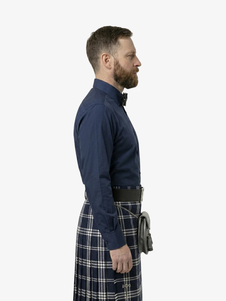 Man wearing a navy shirt and plaid kilt on a white background
