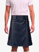 A person wearing a black faux-leather kilt with silver-tone metal hardware, including D-ring details and side pockets, paired with a light pink t-shirt against a plain white background.