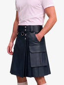 A man wearing a black faux-leather kilt with a matching belt, silver-tone buckle details, and a large front cargo pocket, paired with a light pink t-shirt.