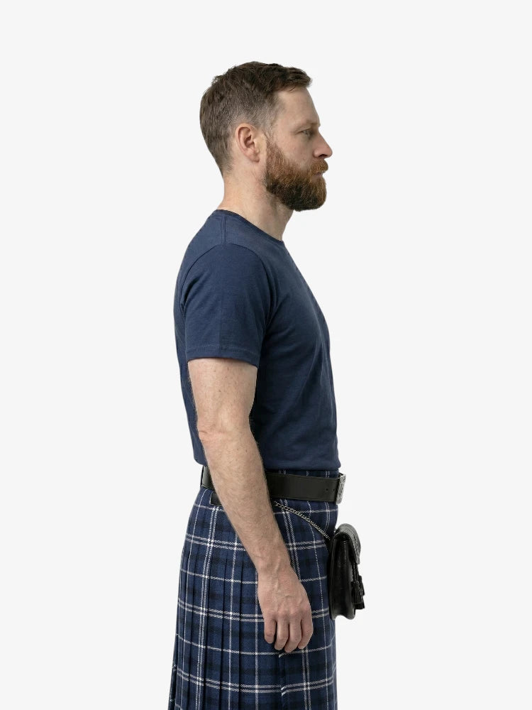 Man wearing a navy t-shirt and plaid kilt on a white background