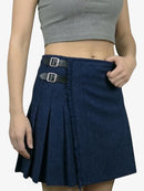 Person wearing a blue denim skirt with silver buckles on a plain background