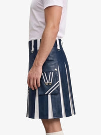 A person wearing a navy blue faux-leather kilt with bold white vertical stripes and silver hardware, paired with a white t-shirt, shown from the side against a light gray background.