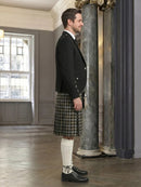 Man wearing a kilt standing in an elegant interior setting with columns.