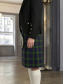 Person wearing a black blazer and plaid kilt in an indoor setting.