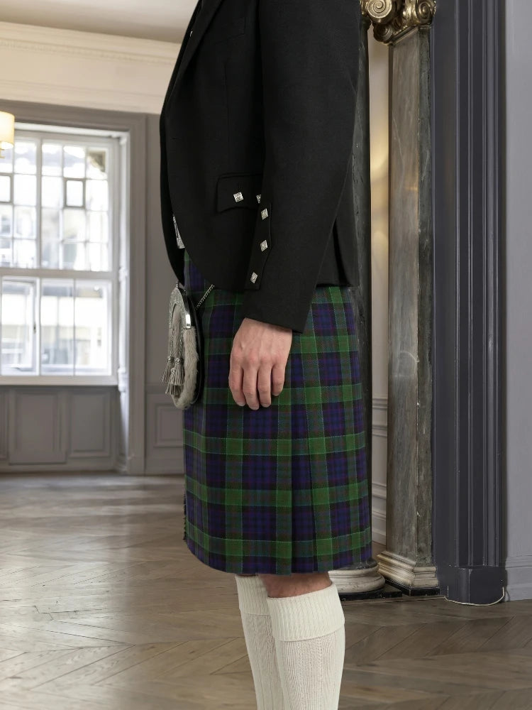 Person wearing a black blazer and plaid kilt in an indoor setting.