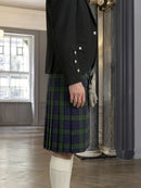 Person wearing a black jacket and plaid kilt in an indoor setting.