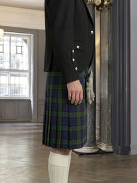 Person wearing a black jacket and plaid kilt in an indoor setting.