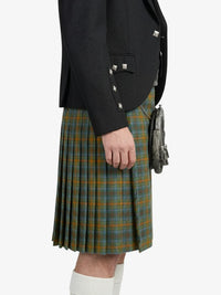 Person wearing a black blazer and green plaid kilt on a white background