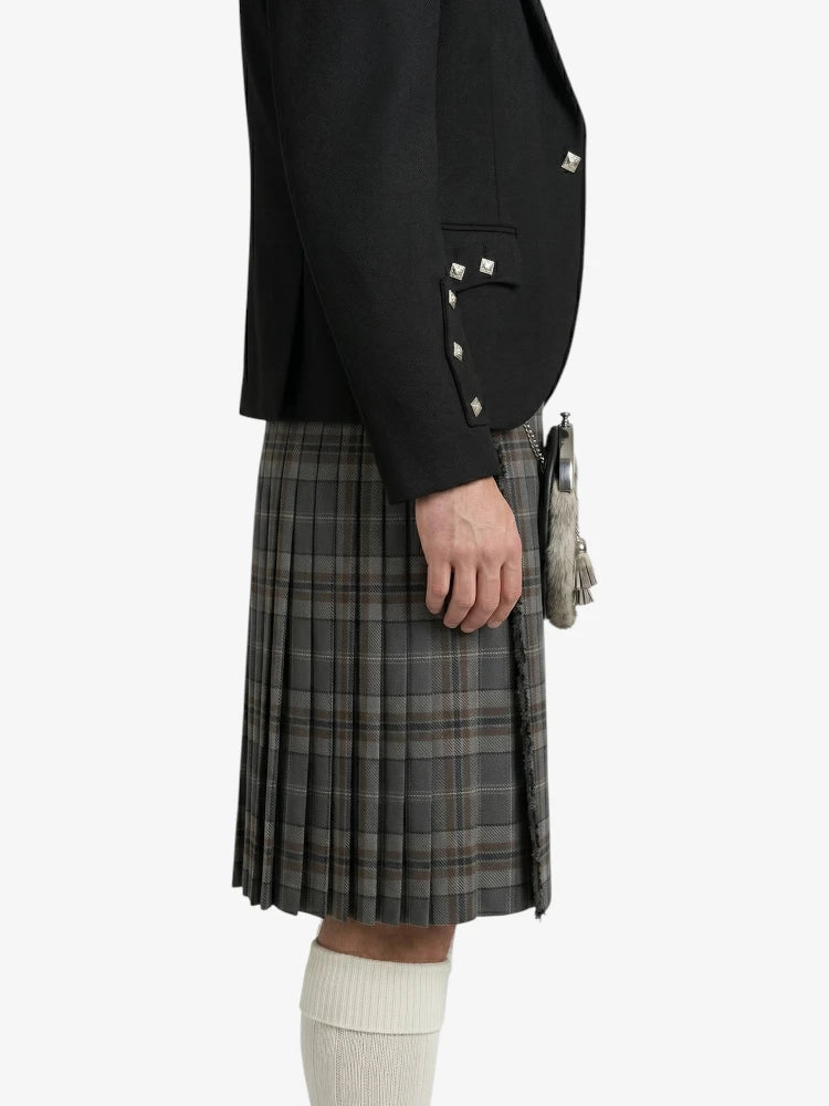 Person wearing a black blazer and plaid kilt on a white background
