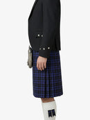 Person wearing a black blazer and blue plaid kilt on a white background