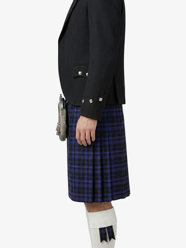 Person wearing a black blazer and blue plaid kilt on a white background