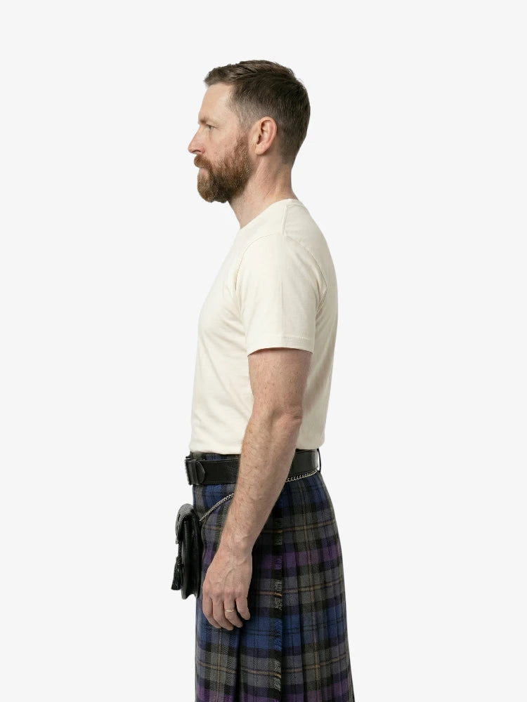 Man wearing a white t-shirt and plaid kilt on a white background