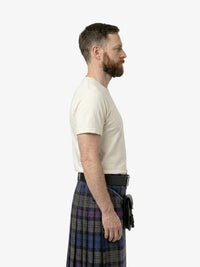 Man wearing a white t-shirt and a plaid kilt on a white background