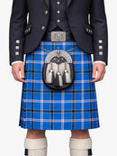 Person wearing a blue plaid kilt with a dark jacket and white socks on a white background