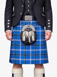 Person wearing a blue plaid kilt with a dark jacket and white socks on a white background