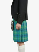 Person wearing a black blazer and green plaid kilt on a white background