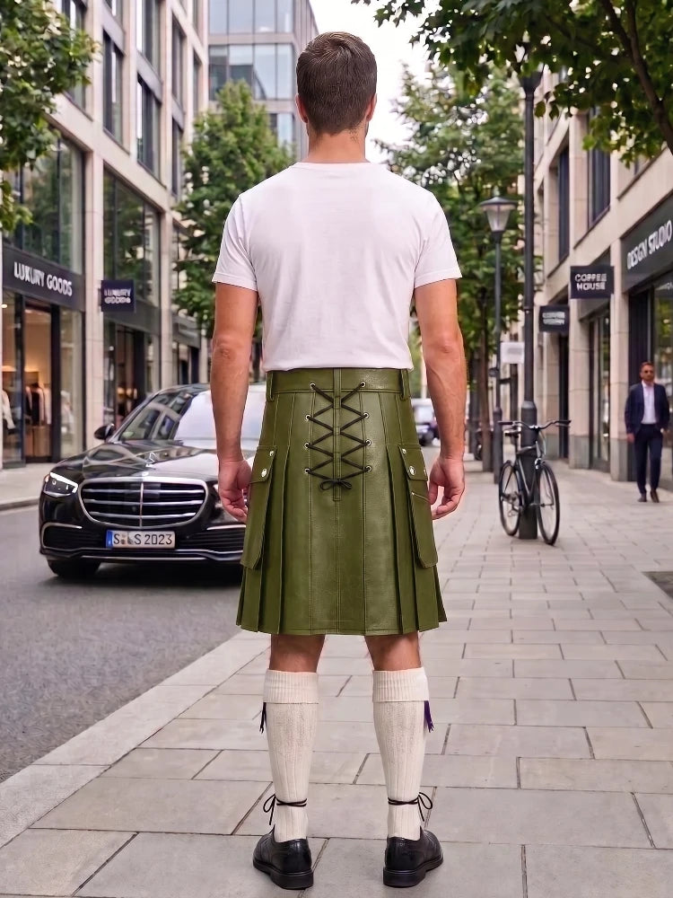 A man viewed from behind wearing an olive green leather kilt with lace-up back detailing, a white t-shirt, white knee-high socks, and black shoes, standing on a city sidewalk.