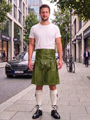 A man standing on a city sidewalk wearing a white t-shirt, an olive green leather kilt with a front pouch, white knee-high socks, and black leather shoes. A black Mercedes-Benz car and urban buildings are visible in the background.