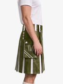 An olive green faux-leather kilt with vertical white stripes, silver-tone metal buttons, and a front flap pocket, shown on a model wearing a white t-shirt against a light gray background.