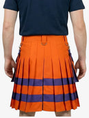 Person wearing an orange and blue pleated skirt with a navy shirt on a white background