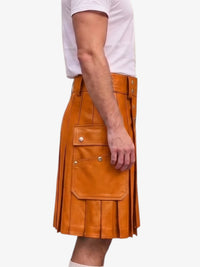 A side view of a person wearing a tan leather kilt with pleats and flap pockets, paired with a white t-shirt, against a plain light gray background.