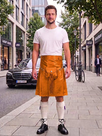 A man stands on a city sidewalk wearing a mustard yellow leather kilt over a white t-shirt, white knee-high socks, and black leather shoes. A black Mercedes-Benz car and a bicycle are visible in the background of the street scene.