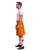 A man shown in profile wearing a bright orange leather kilt, a white t-shirt, white socks, and black shoes, isolated on a white background.