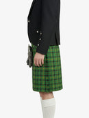 Person wearing a black jacket and green plaid kilt on a white background
