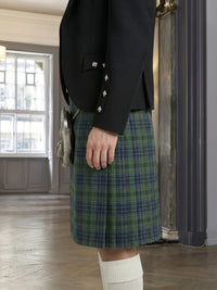 Person wearing a black jacket and green plaid kilt indoors.