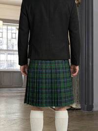 Person wearing a black jacket and green plaid kilt indoors.
