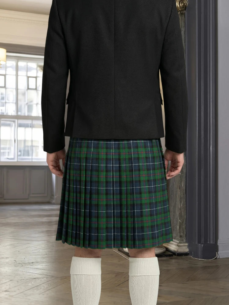 Person wearing a black jacket and green plaid kilt indoors.