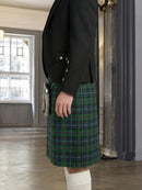 Person wearing a black blazer and green plaid kilt in an indoor setting.