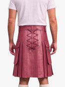 A person shown from the back wearing a pleated kilt in dusty rose pink faux leather with a lace-up back closure and side cargo pockets, paired with a light pink t-shirt and white socks against a light gray background.