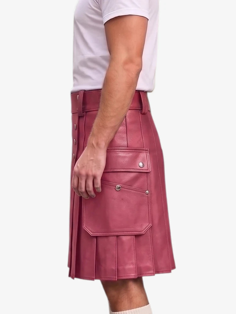 A person wearing a dusty rose pink faux-leather kilt with pleated detailing and flap pockets, paired with a white t-shirt, shown from a side profile against a light gray background.