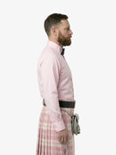 Man wearing a pink dress shirt and plaid kilt on a white background