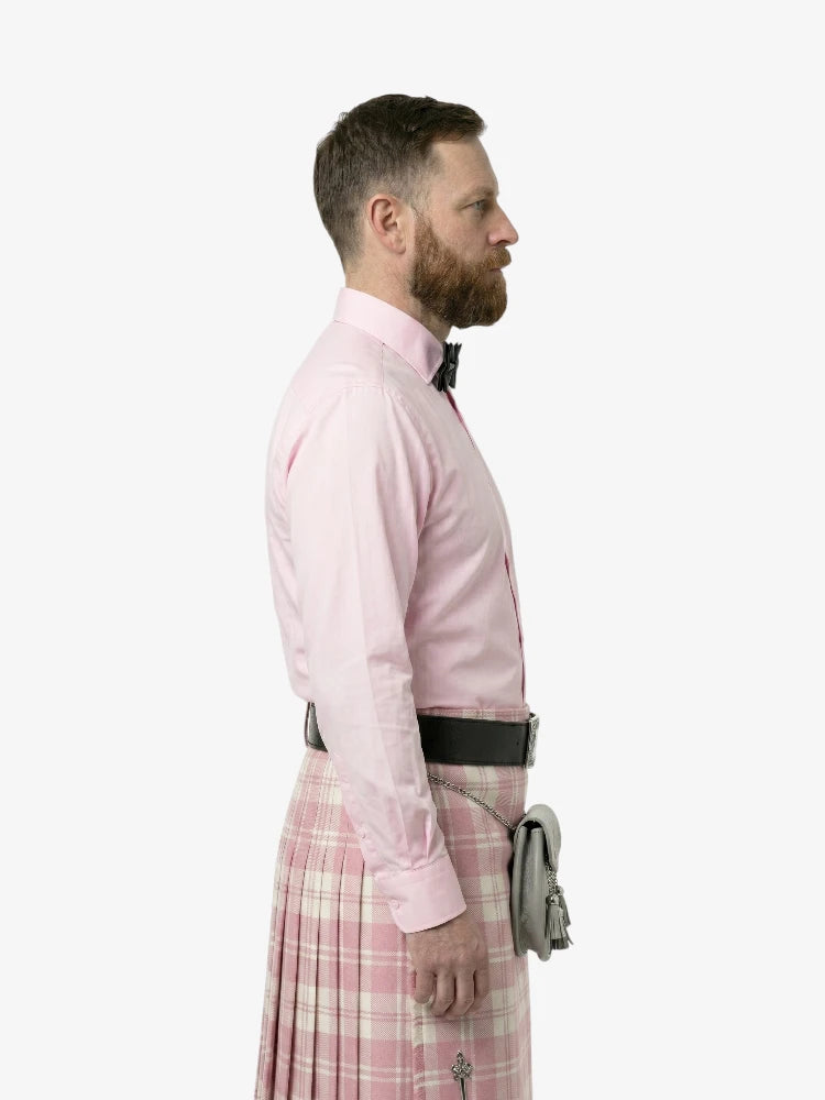 Man wearing a pink dress shirt and plaid kilt on a white background
