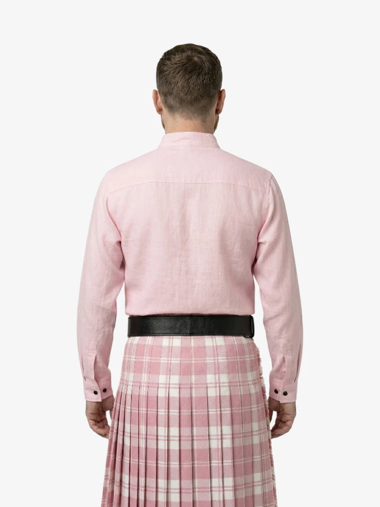 Man wearing a pink shirt and plaid kilt on a white background