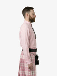 Man wearing a pink shirt and plaid skirt on a white background