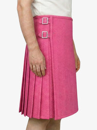 Person wearing a pink pleated skirt with silver buckles on a white background