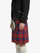 Person wearing a black blazer and red plaid kilt on a white background