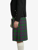 Person wearing a black jacket and green plaid kilt on a white background