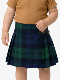 Child wearing a green plaid skirt and brown shirt on a white background