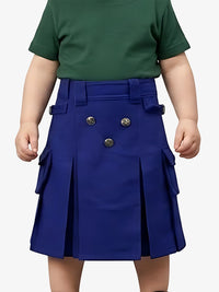 Child wearing a green shirt and blue pleated skirt with gold buttons on a white background