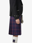 Person wearing a black jacket and plaid kilt on a white background