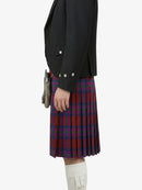 Person wearing a black blazer and red plaid kilt on a white background