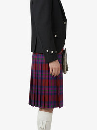 Person wearing a black jacket and red plaid kilt on a white background