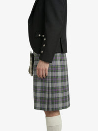 Person wearing a black jacket and plaid kilt on a white background